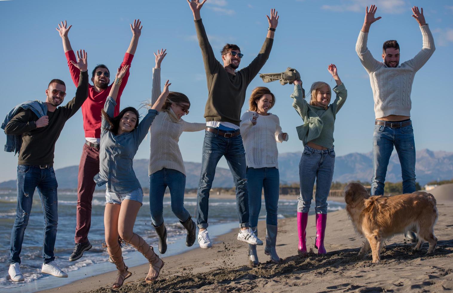 young friends jumping together at autumn beach photo