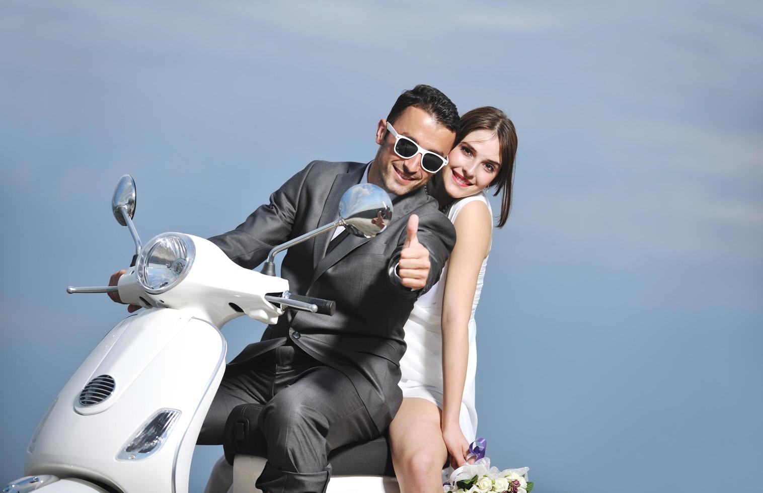 pareja de recién casados en la playa paseo scooter blanco foto