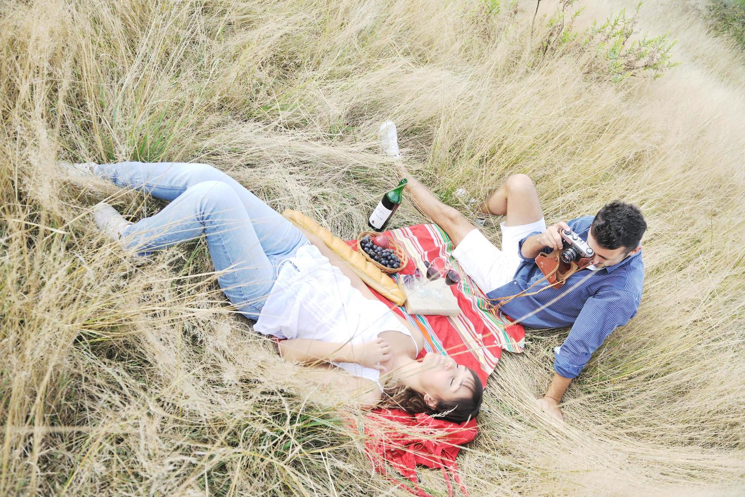 happy couple enjoying countryside picnic in long grass photo