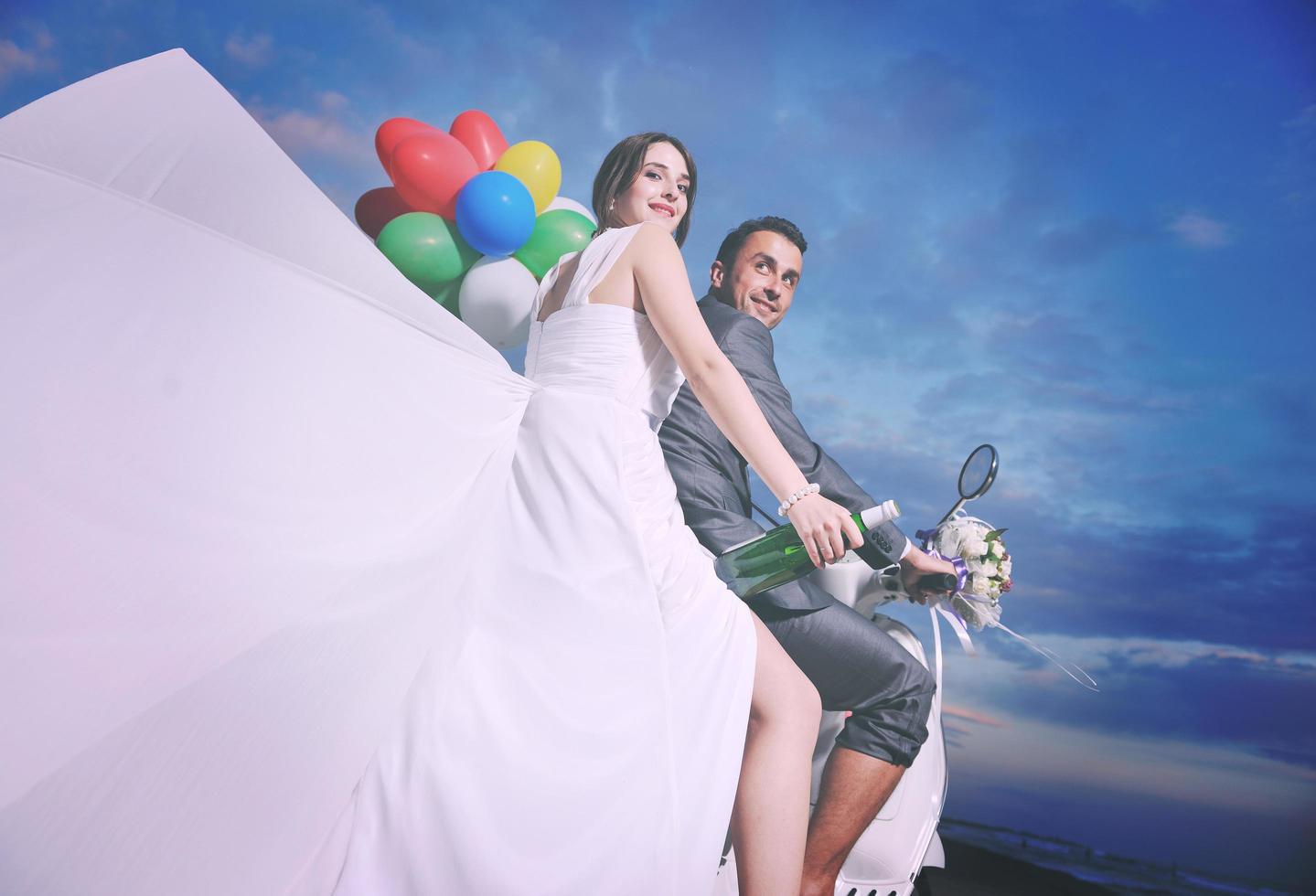 just married couple on the beach ride white scooter photo