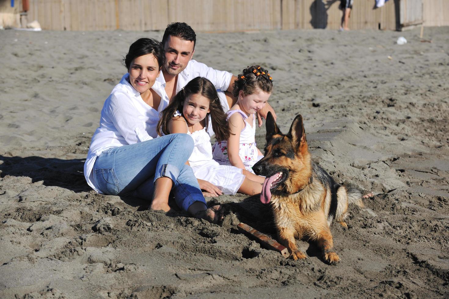 familia feliz jugando con el perro en la playa foto