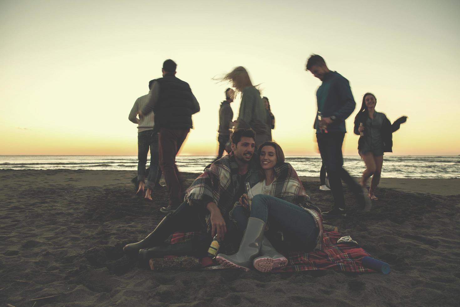 Couple enjoying with friends at sunset on the beach photo