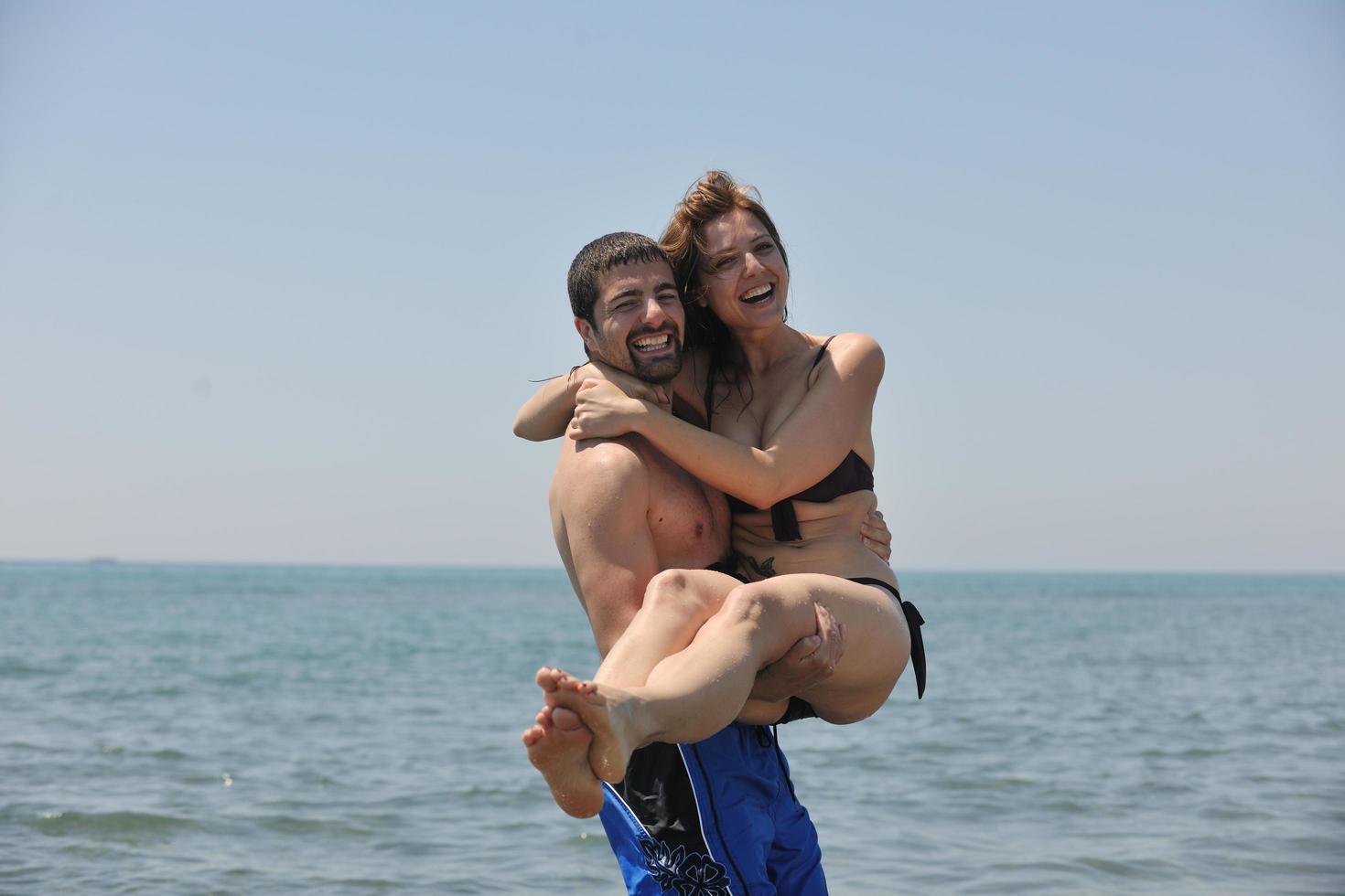 feliz pareja joven divertirse en la playa foto