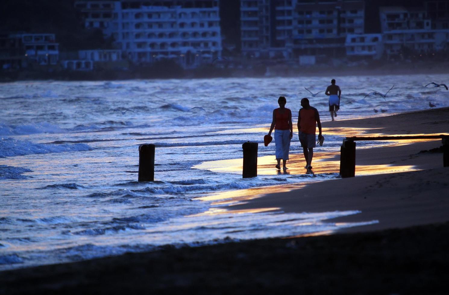 romantic couple walking on beach at sunset photo