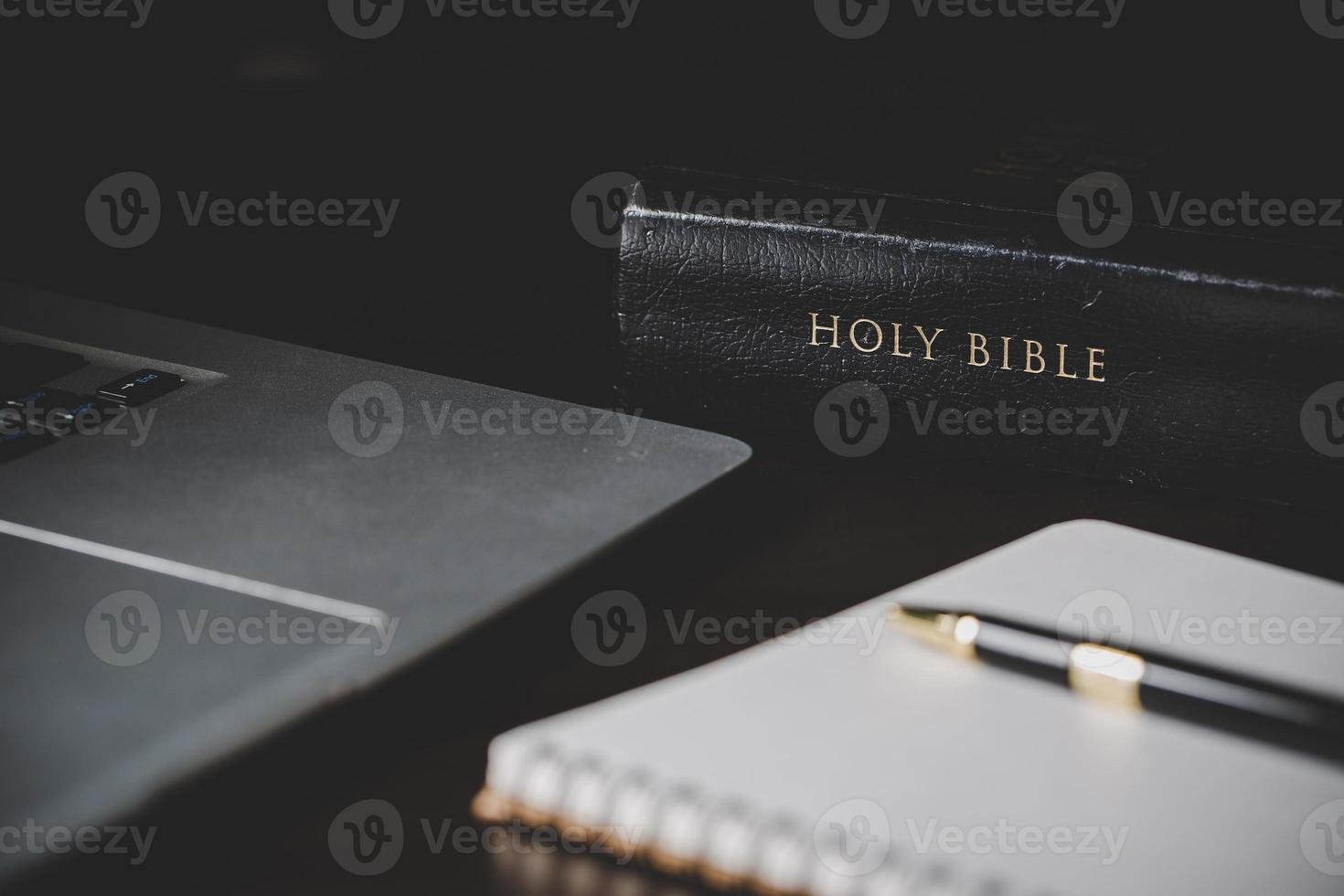 Holy bible book with paper for education on black wooden background. Christian catholic with protestant worship and pray in church. Concept of learning about faith god and religion, jesus spiritual. photo