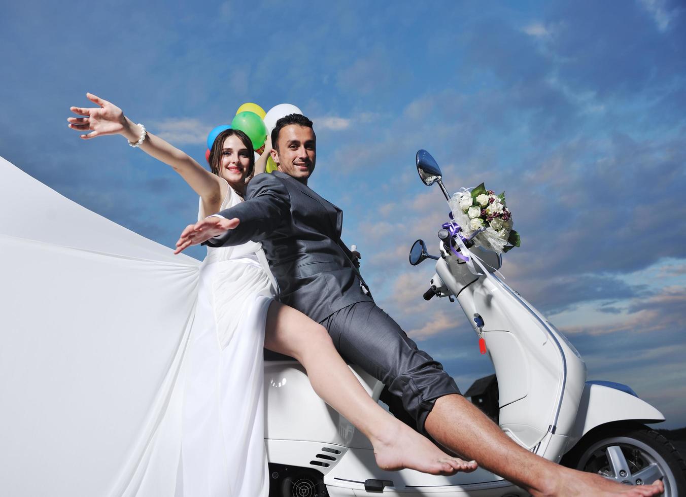 just married couple on the beach ride white scooter photo