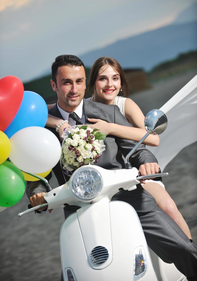 just married couple on the beach ride white scooter photo