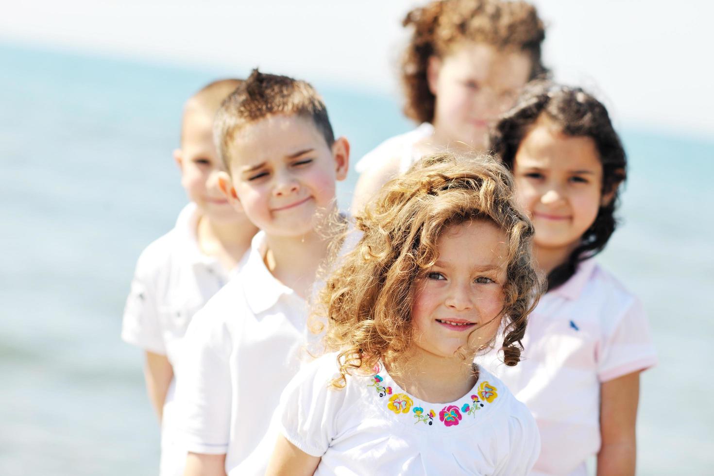 Grupo de niños felices jugando en la playa foto