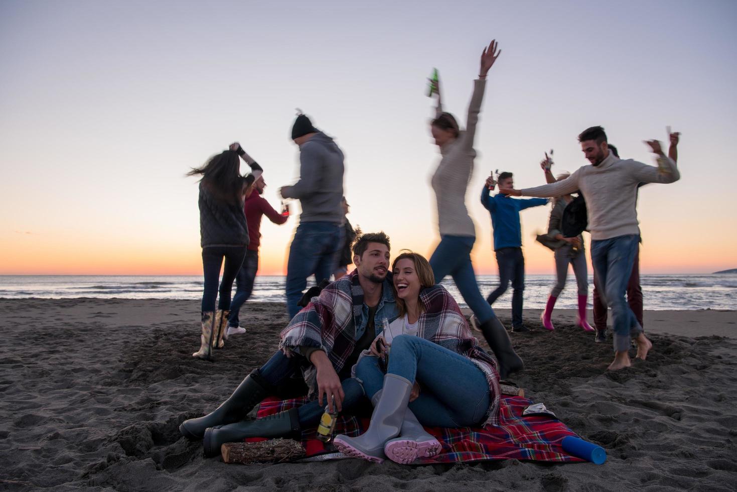 Couple enjoying with friends at sunset on the beach photo