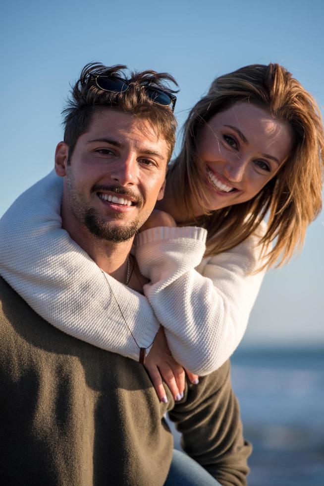 pareja divirtiéndose en la playa durante el otoño foto