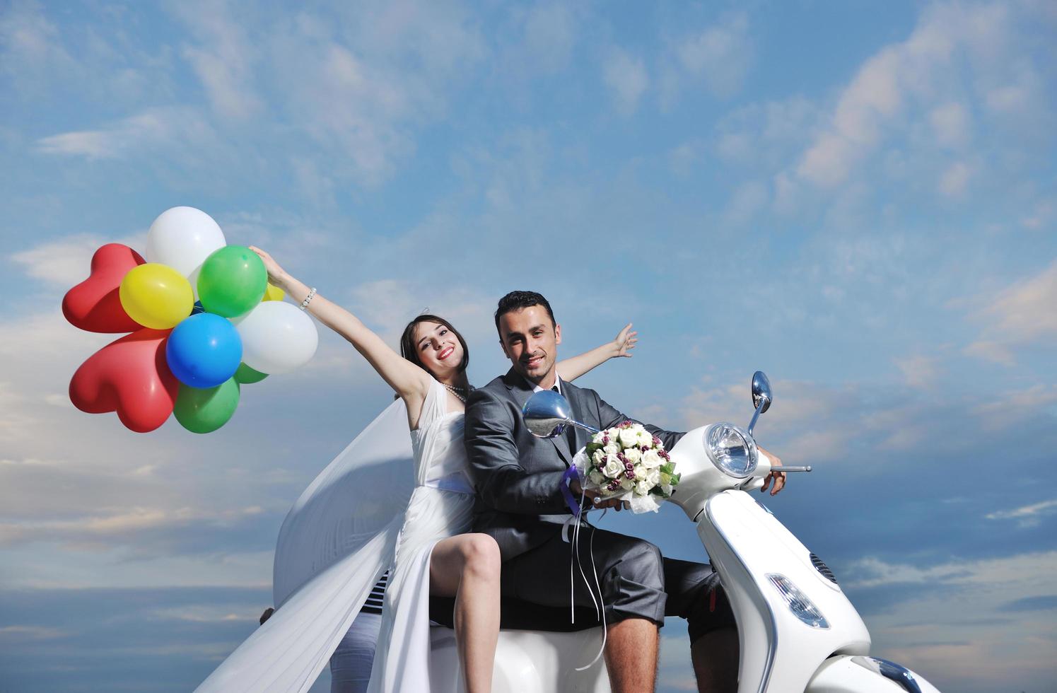 just married couple on the beach ride white scooter photo