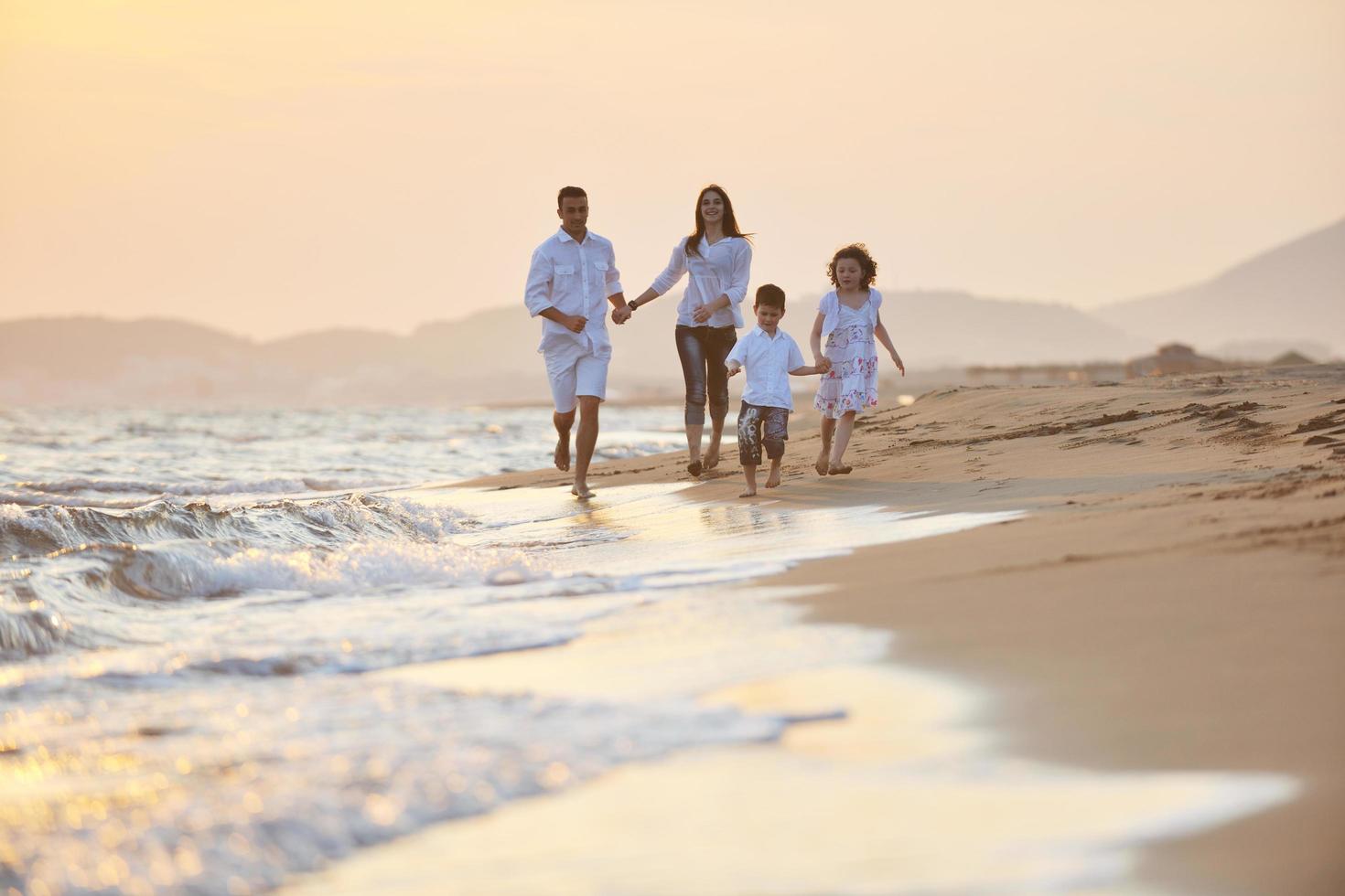 familia joven feliz divertirse en la playa al atardecer foto