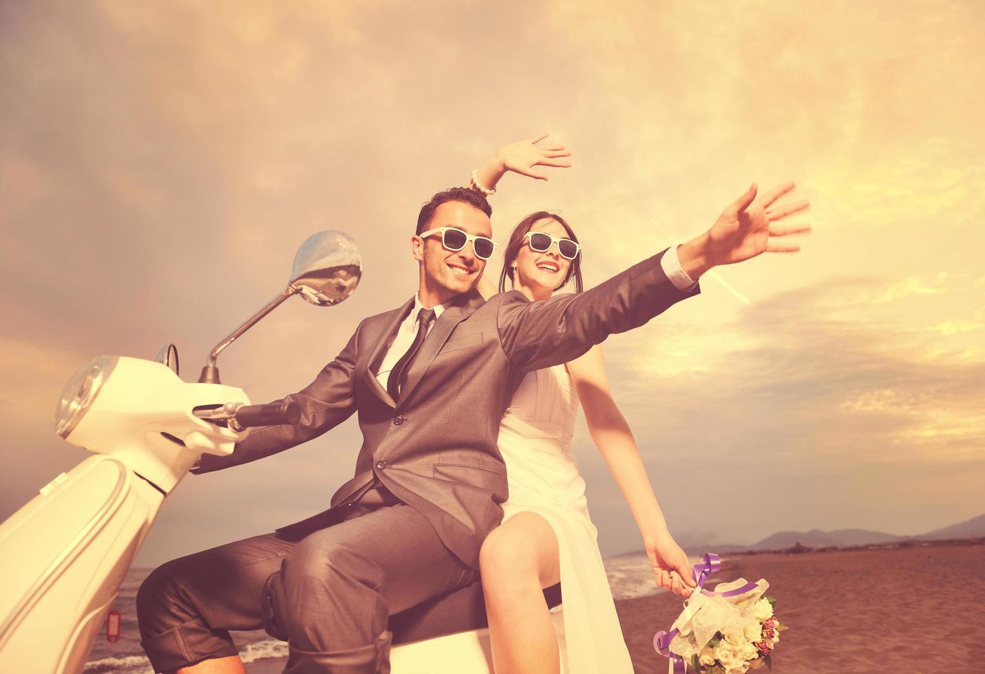 pareja de recién casados en la playa paseo scooter blanco foto