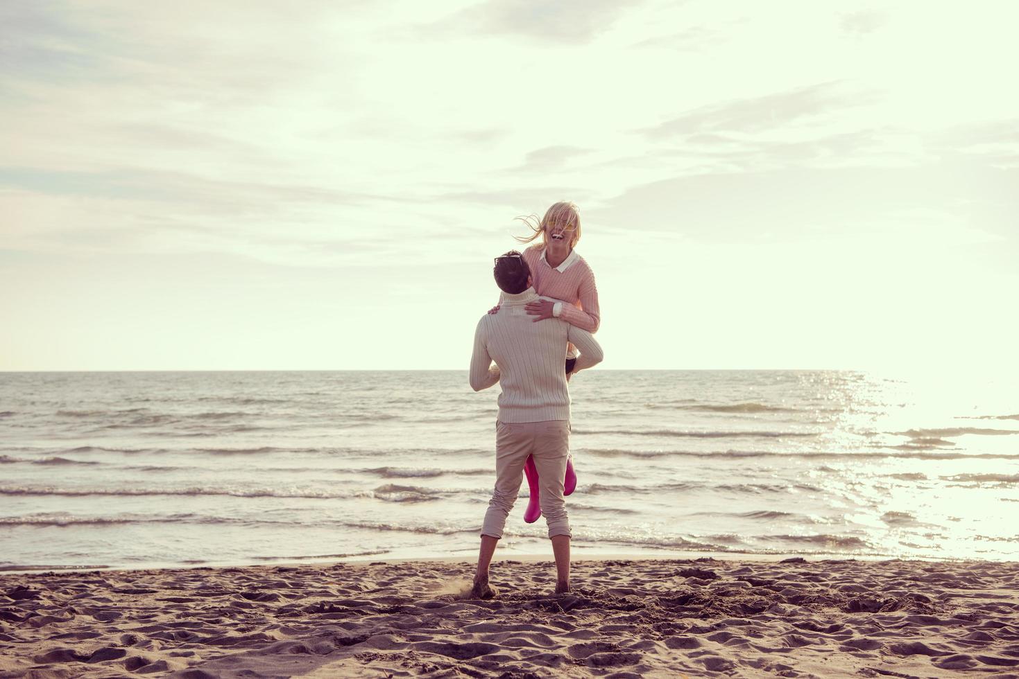 Loving young couple on a beach at autumn sunny day photo