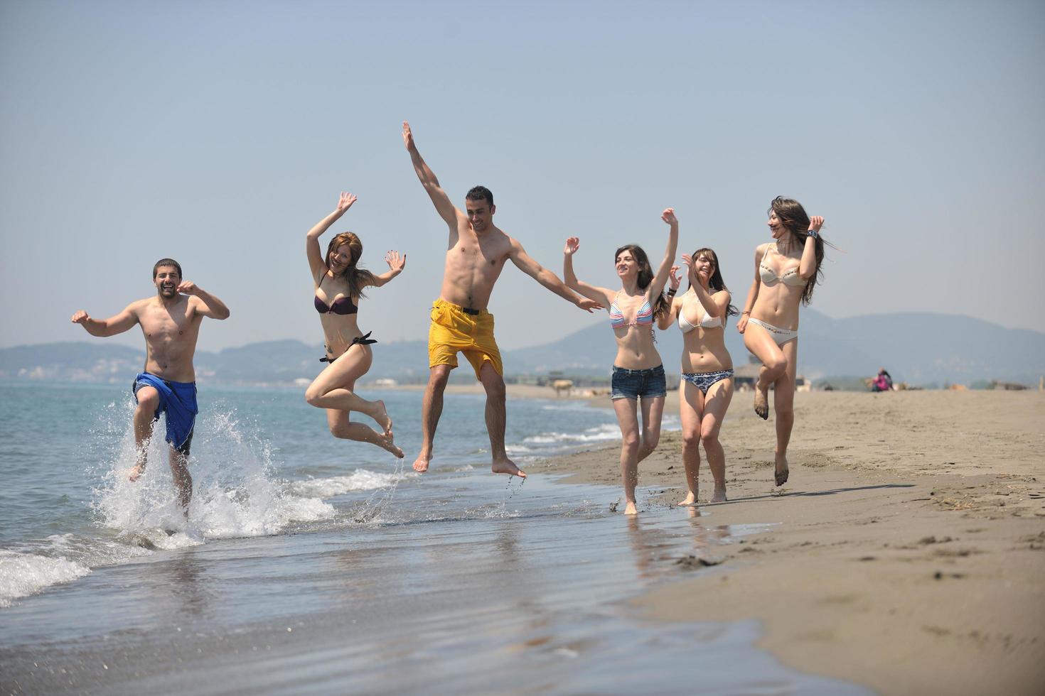 grupo de gente feliz divertirse y correr en la playa foto