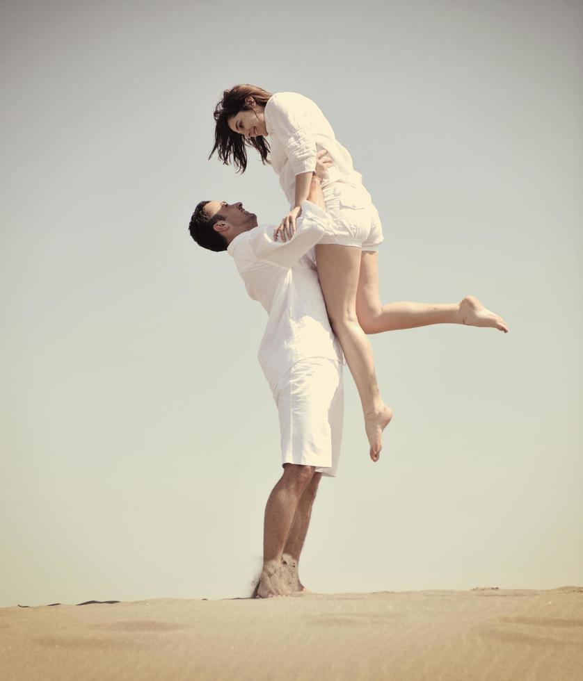 feliz pareja joven divertirse en la playa foto