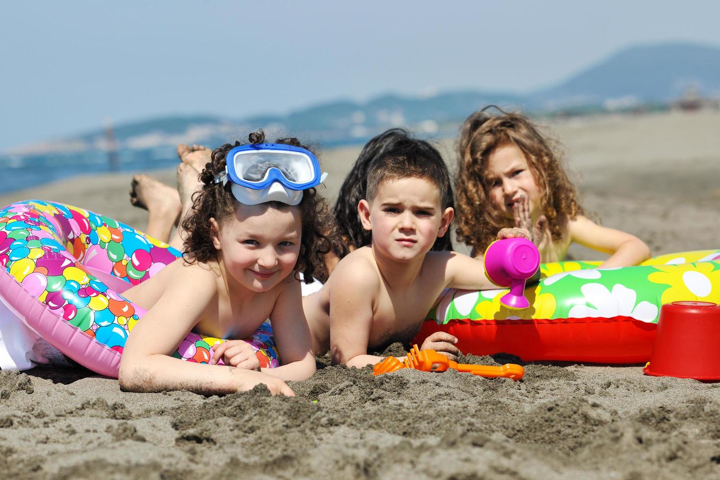 grupo infantil divertirse y jugar con juguetes de playa foto