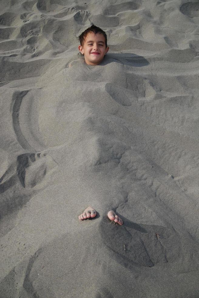 niños felices enterrados en la arena foto