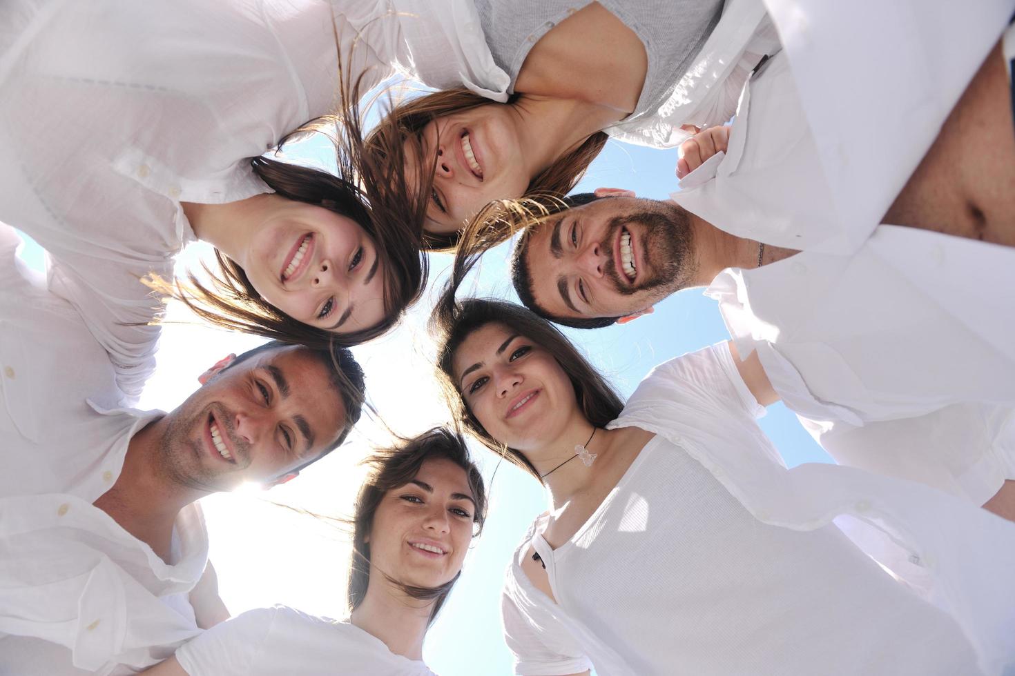 Group of happy young people in circle at beach photo