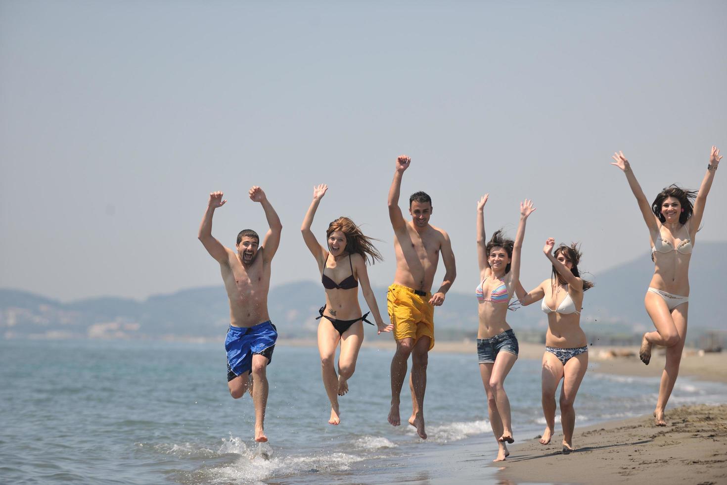 grupo de gente feliz divertirse y correr en la playa foto