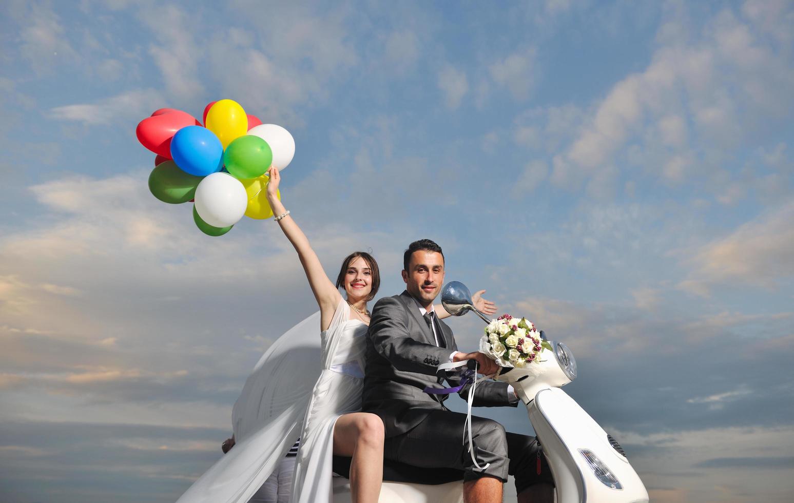 just married couple on the beach ride white scooter photo