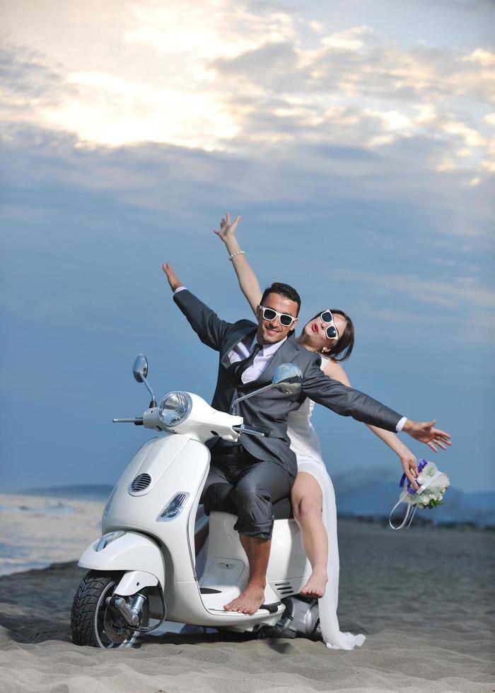 pareja de recién casados en la playa paseo scooter blanco foto