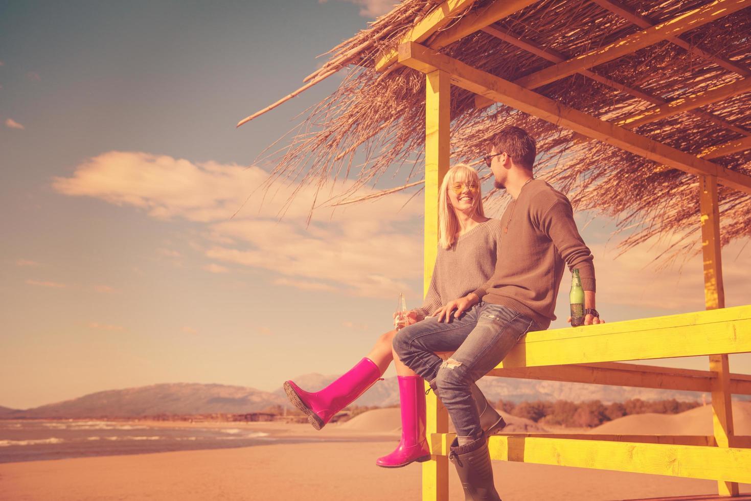 young couple drinking beer together at the beach photo