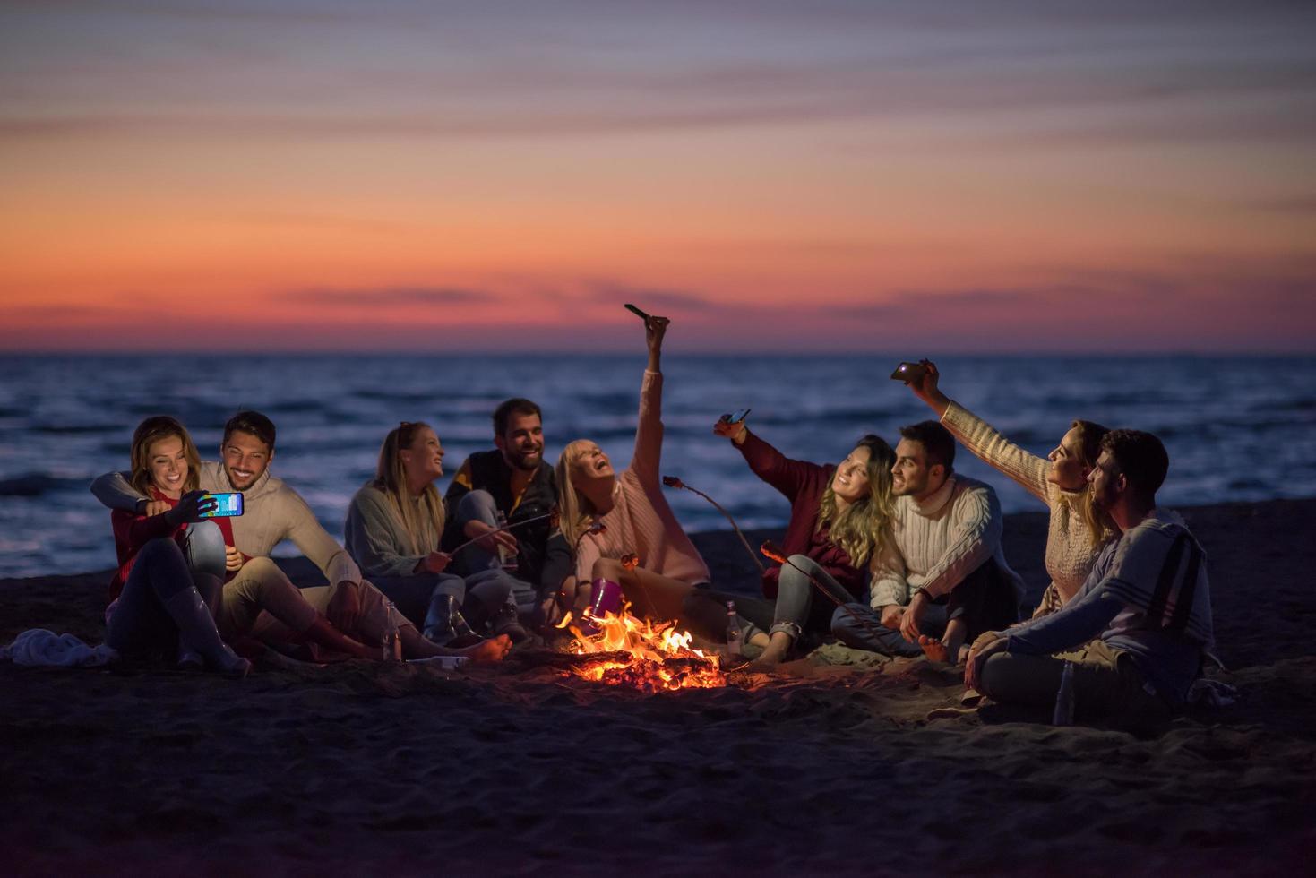 a group of friends enjoying bonfire on beach photo