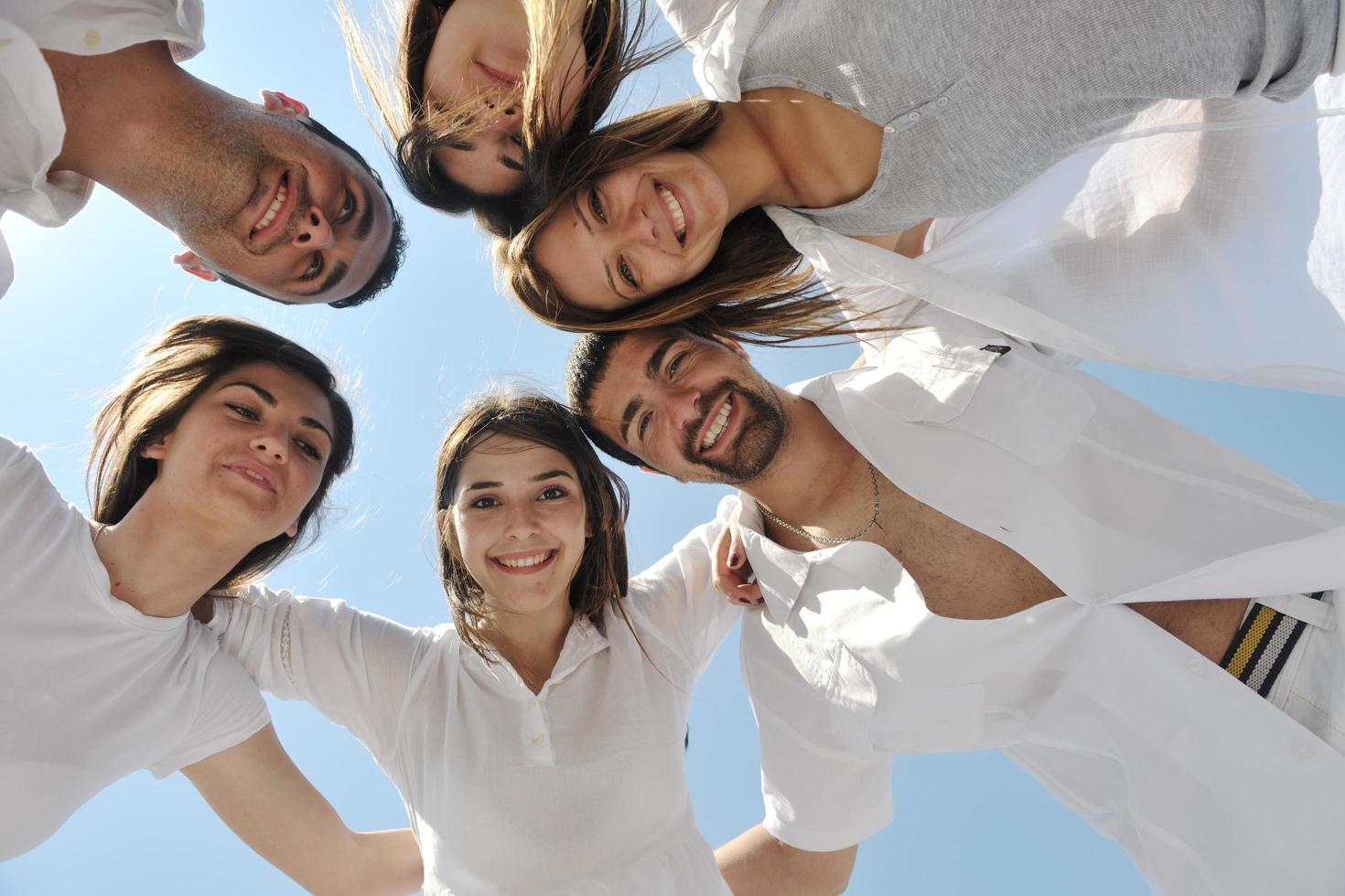 grupo de jóvenes felices en círculo en la playa foto