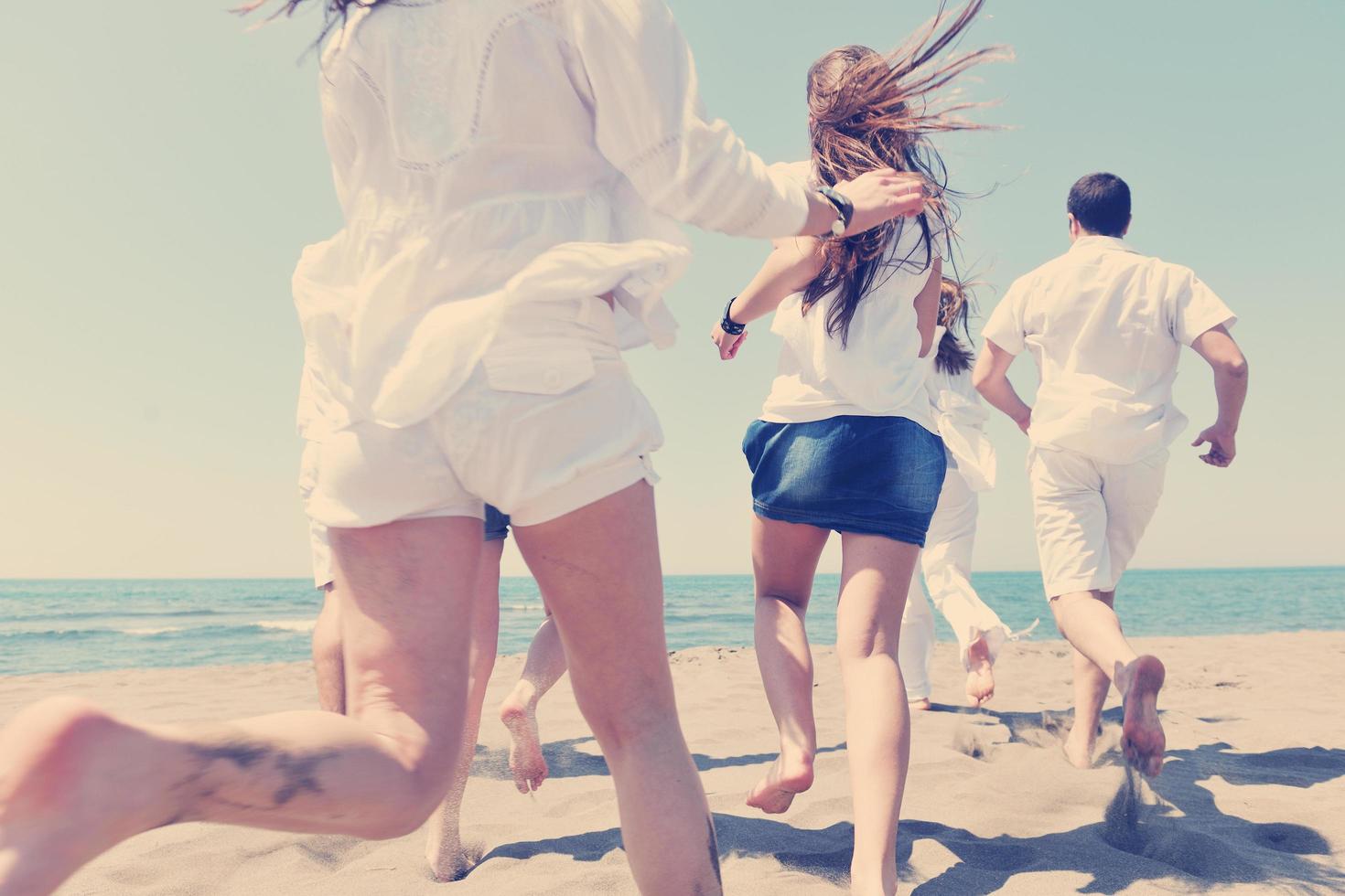 grupo de gente feliz divertirse y correr en la playa foto