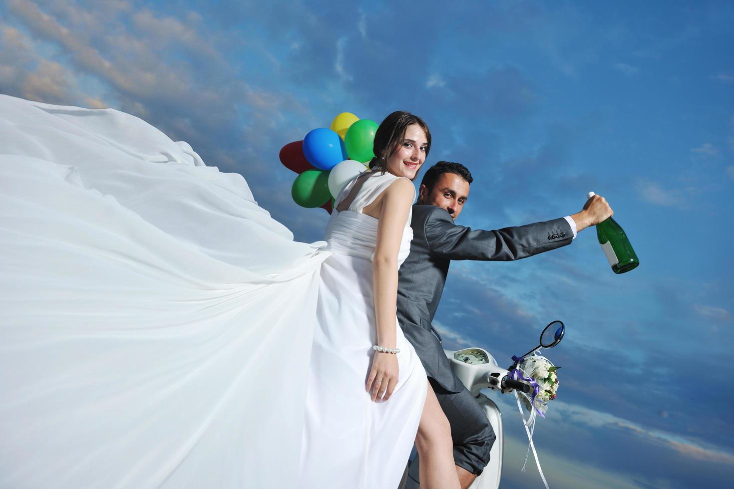 just married couple on the beach ride white scooter photo
