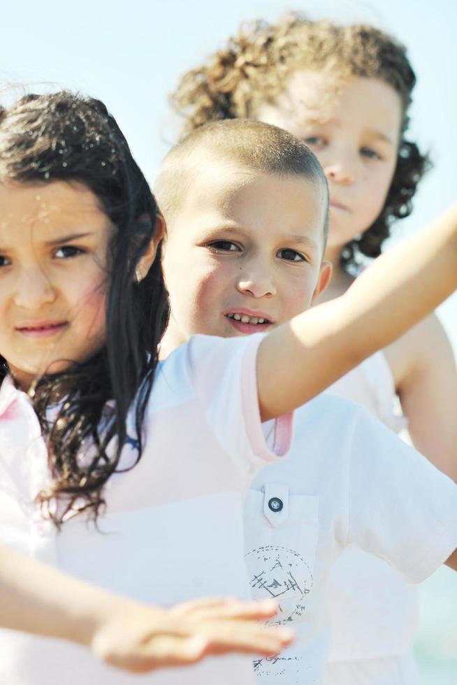 Grupo de niños felices jugando en la playa foto