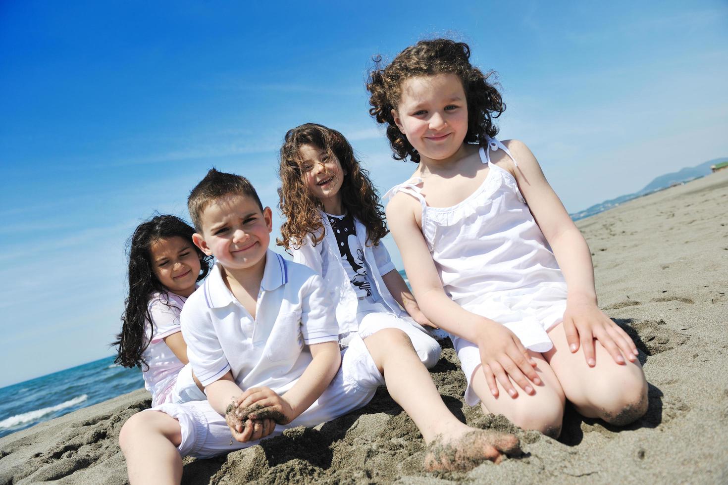 Grupo de niños felices jugando en la playa foto