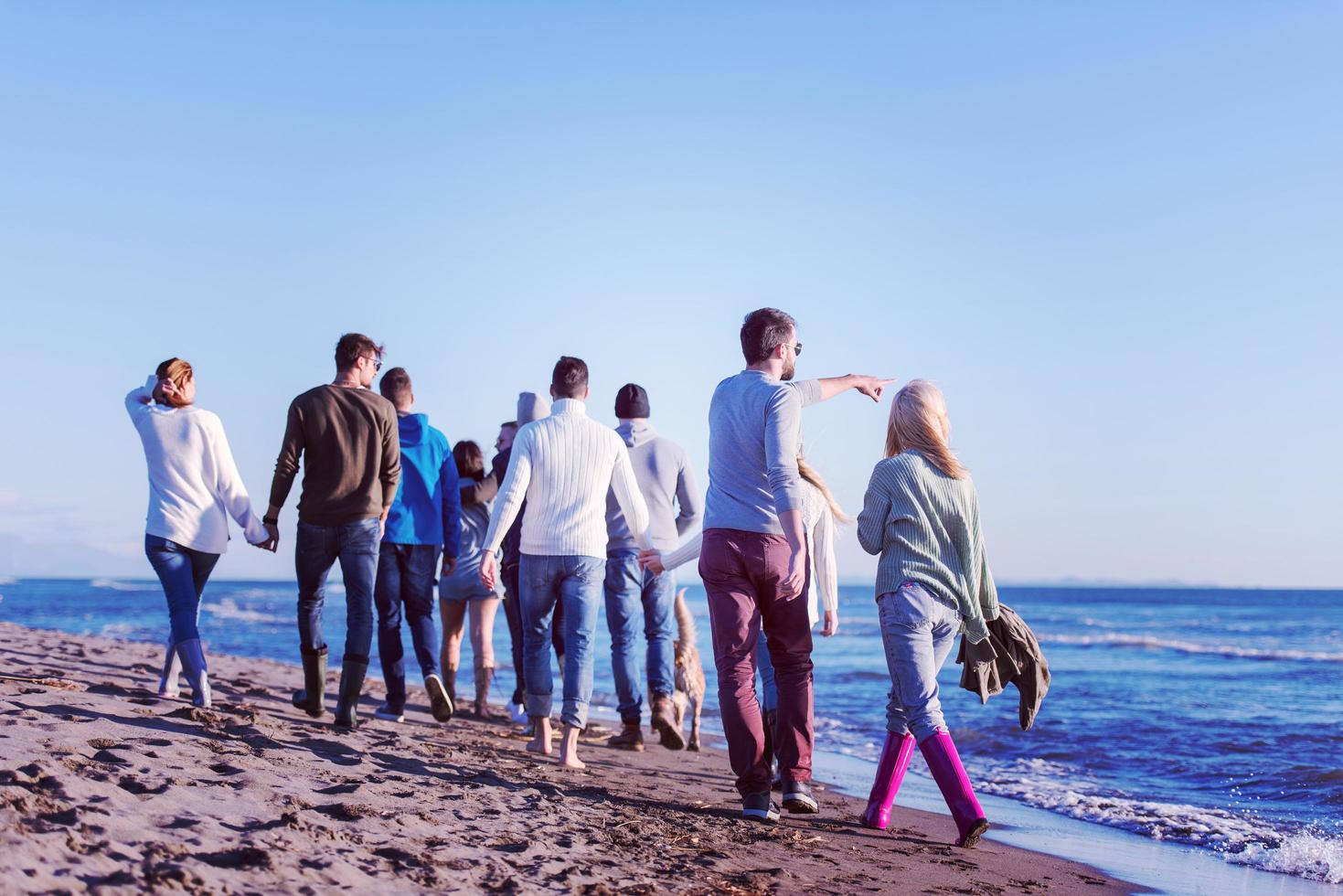 Group of friends running on beach during autumn day photo