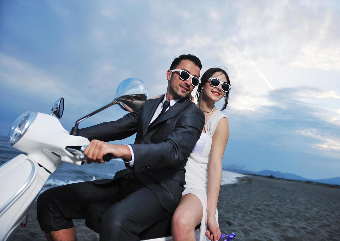 just married couple on the beach ride white scooter photo