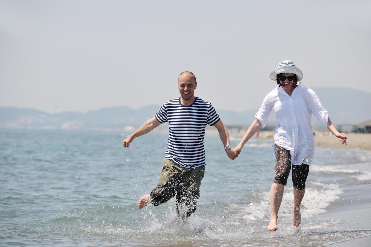 feliz pareja joven divertirse en la playa foto