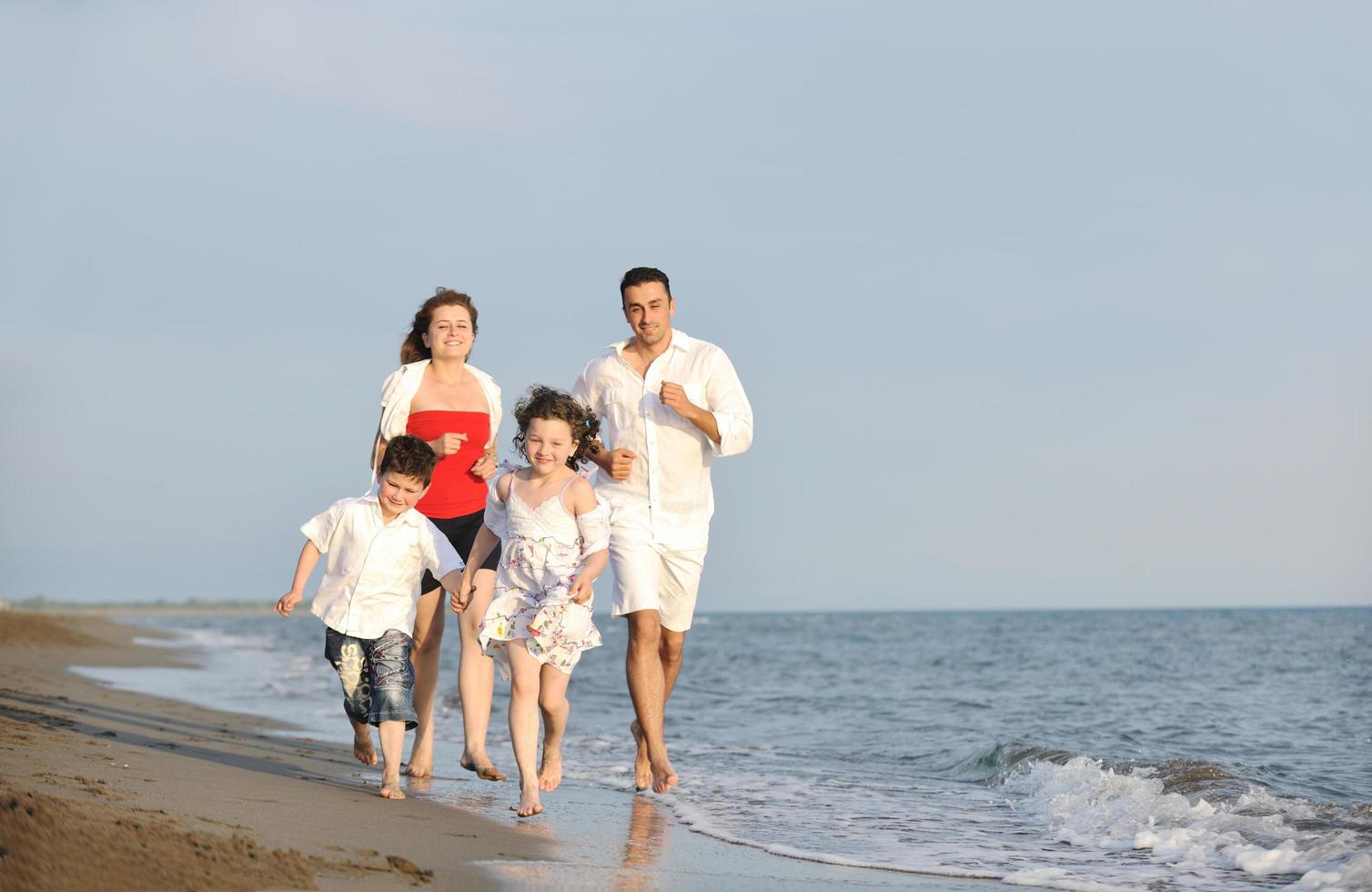 familia joven feliz divertirse en la playa foto