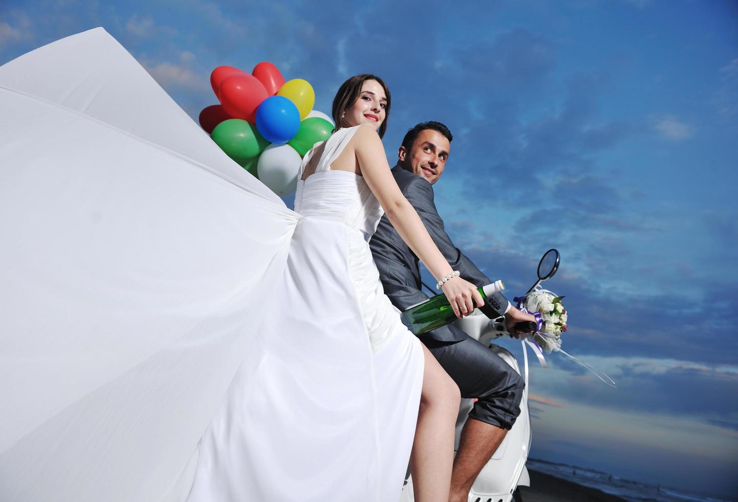 just married couple on the beach ride white scooter photo