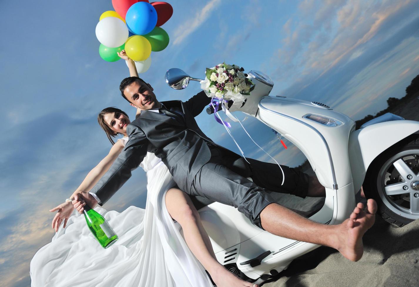 just married couple on the beach ride white scooter photo