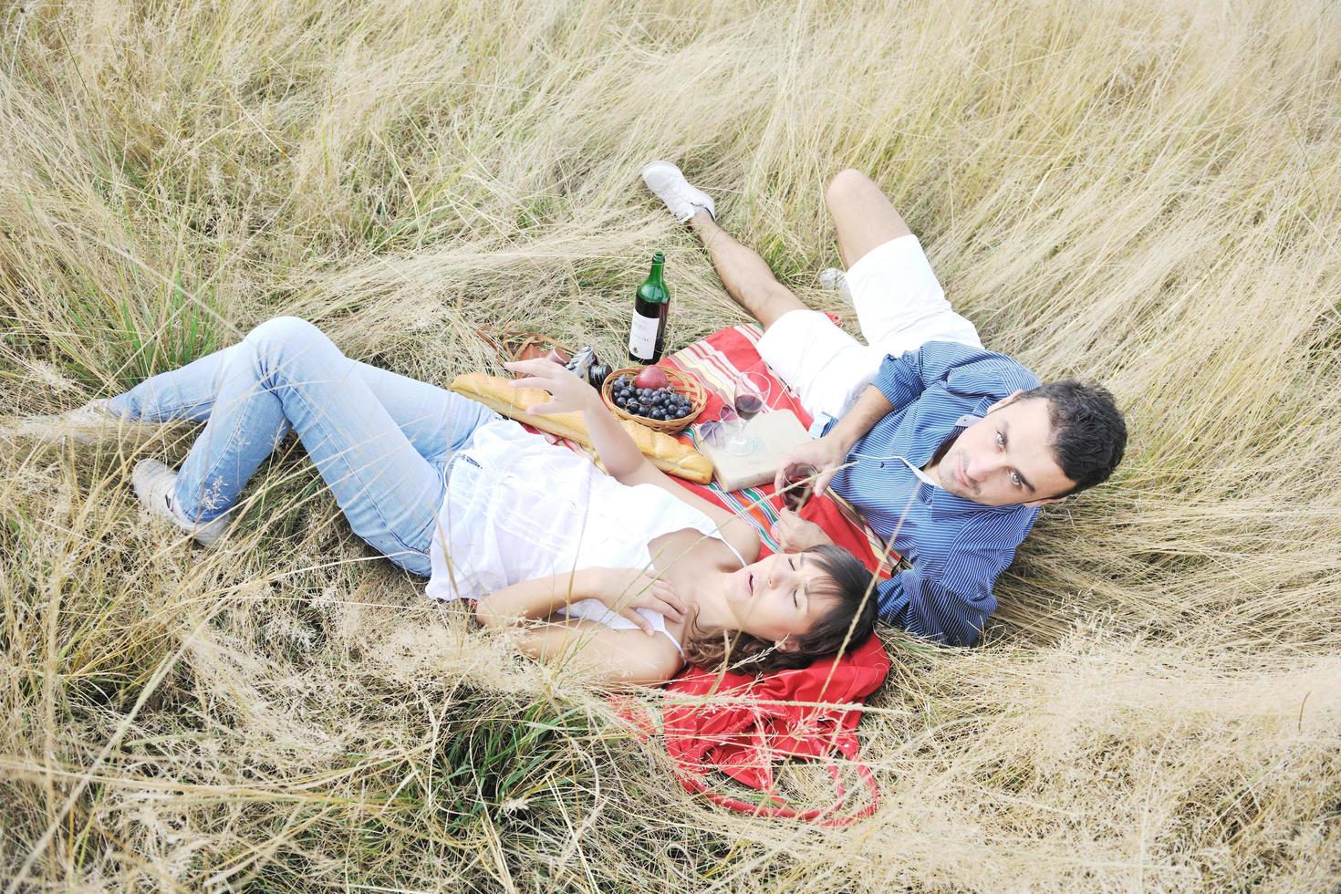 happy couple enjoying countryside picnic in long grass photo