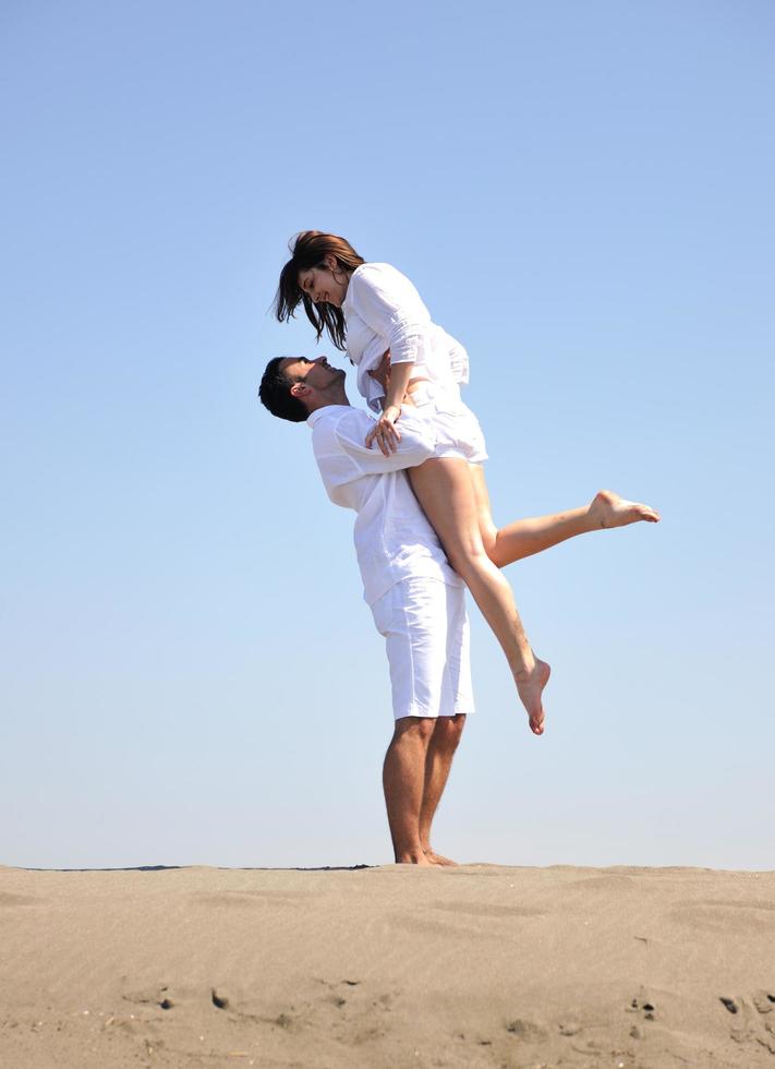 feliz pareja joven divertirse en la playa foto