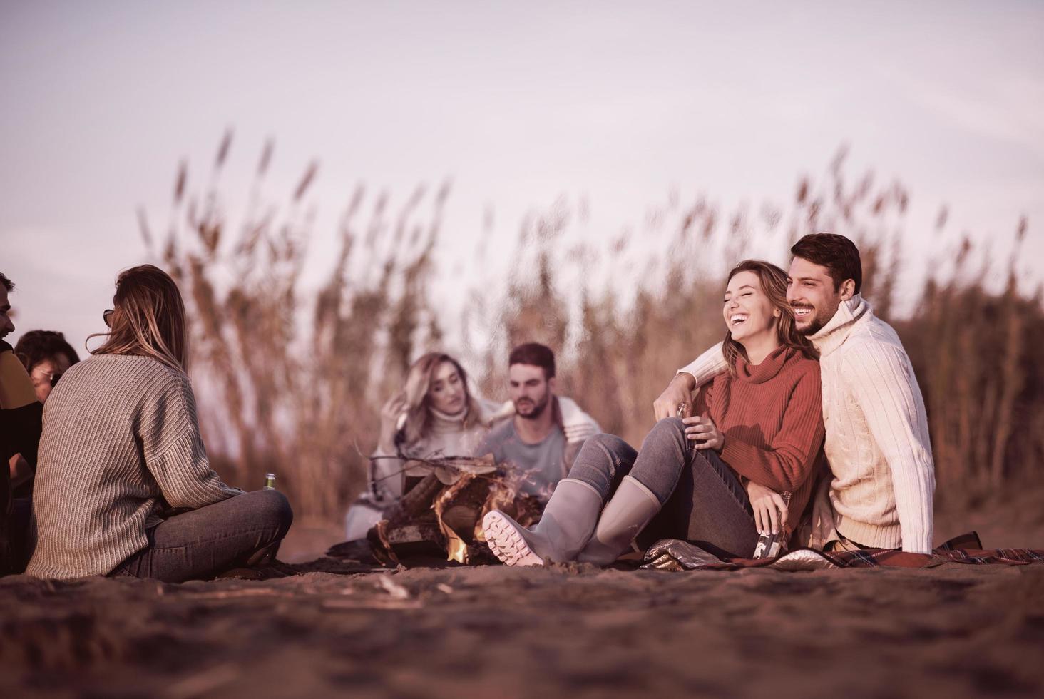 Couple enjoying with friends at sunset on the beach photo