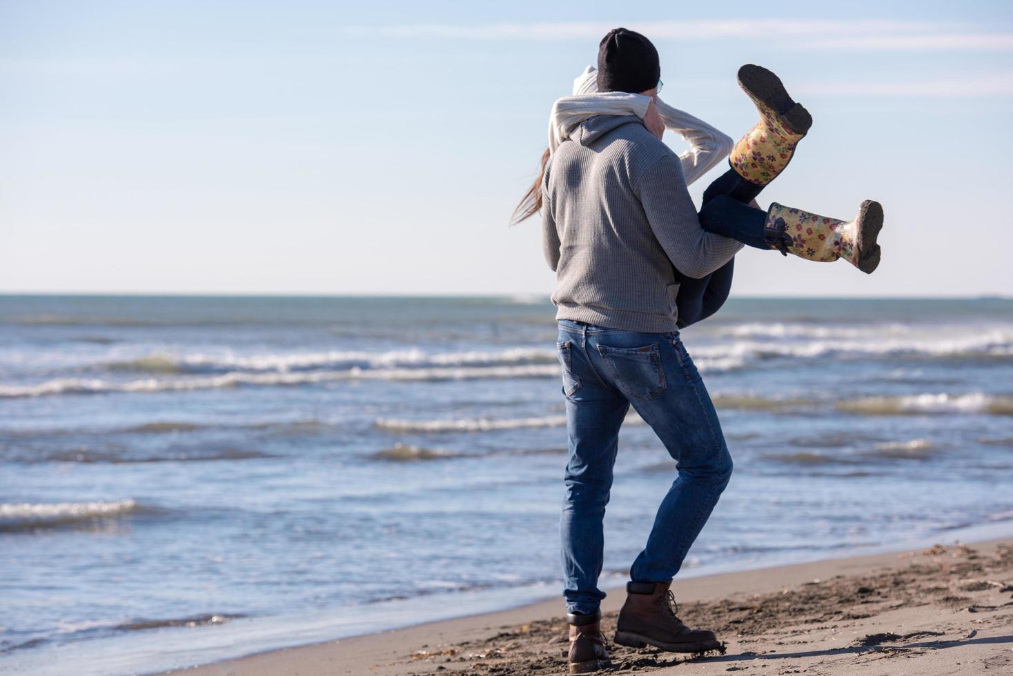 Loving young couple on a beach at autumn sunny day photo