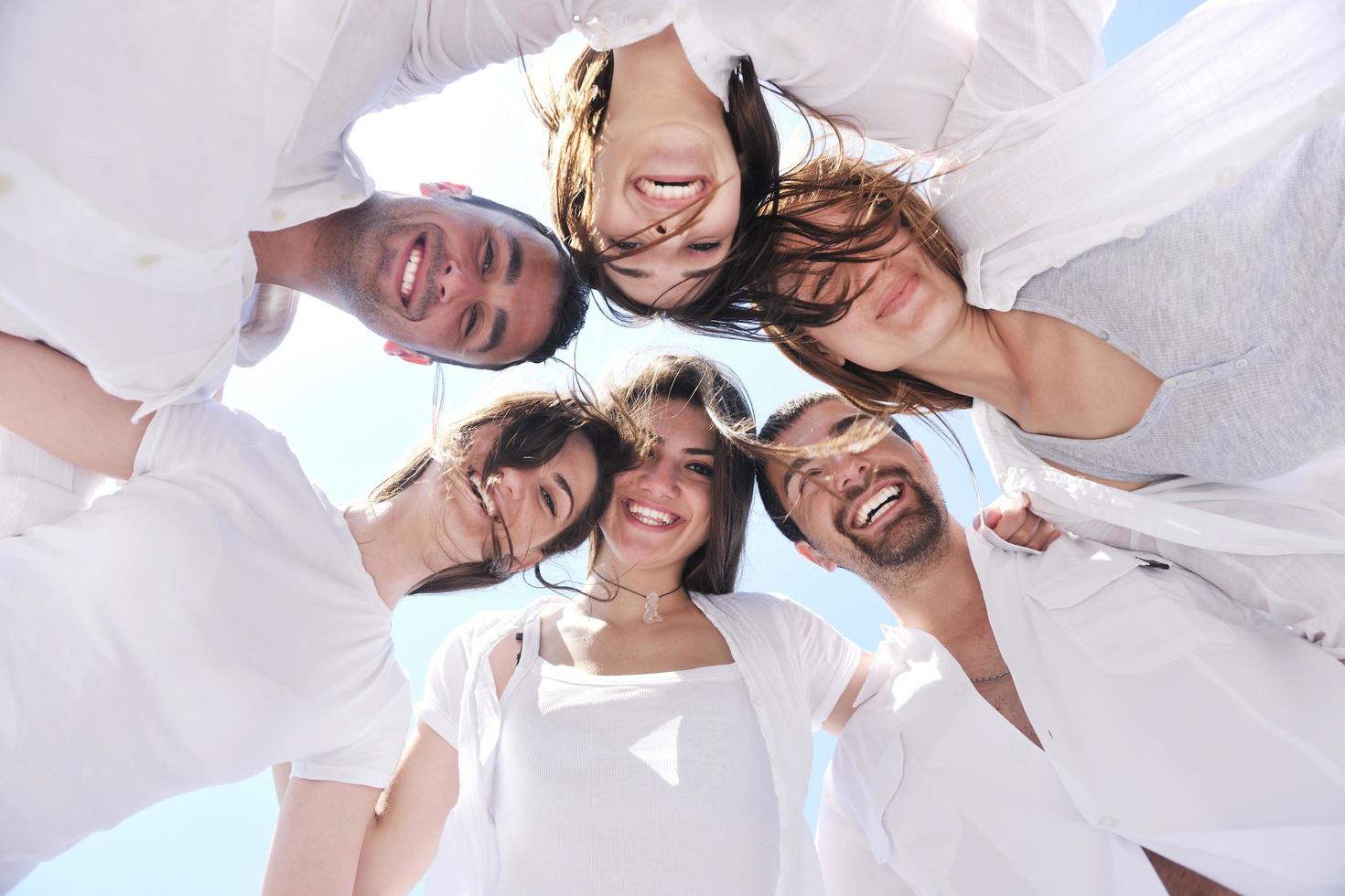 Group of happy young people in circle at beach photo