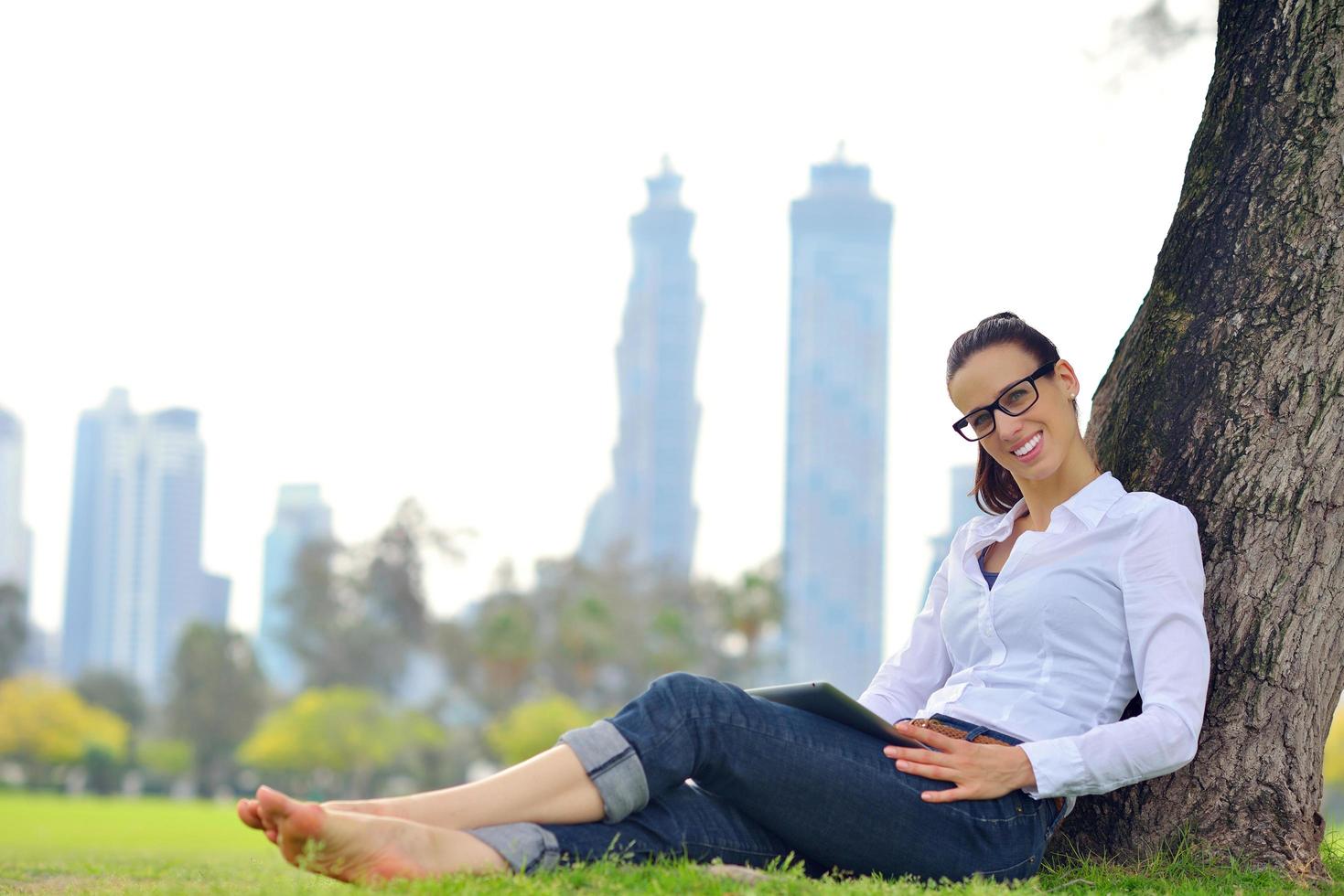 Beautiful young woman with  tablet in park photo