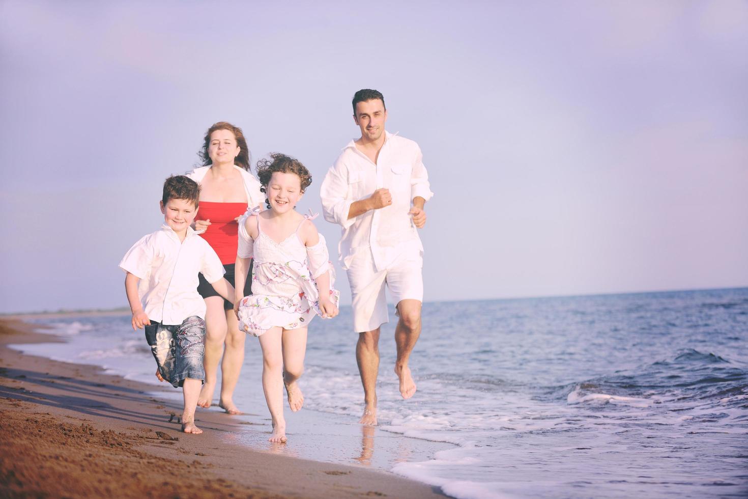 familia joven feliz divertirse en la playa foto