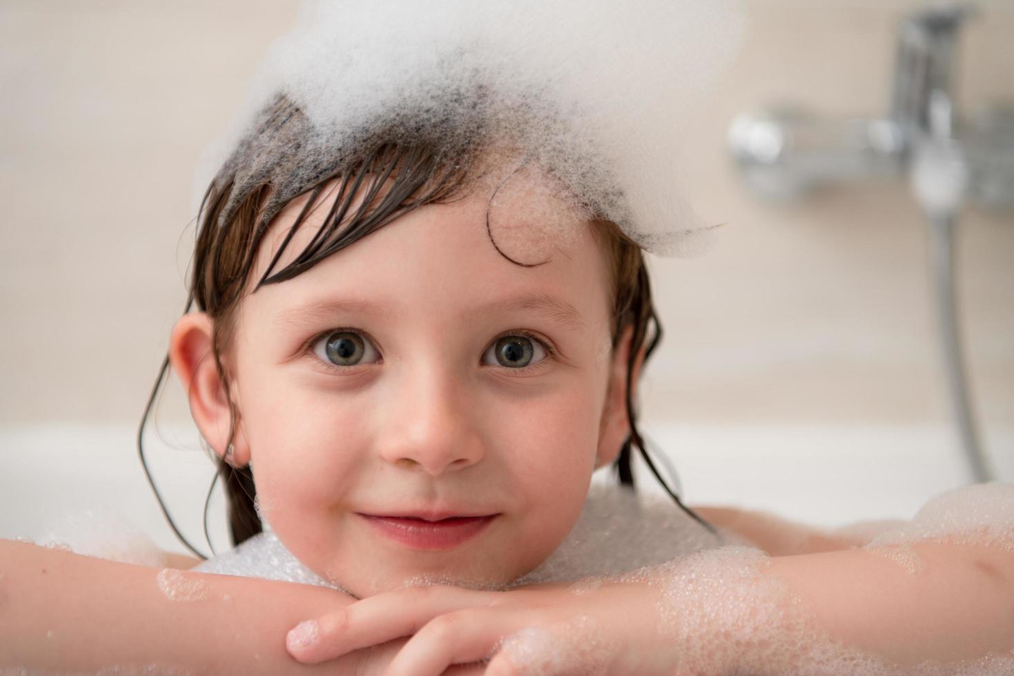 little girl in bath playing with foam photo