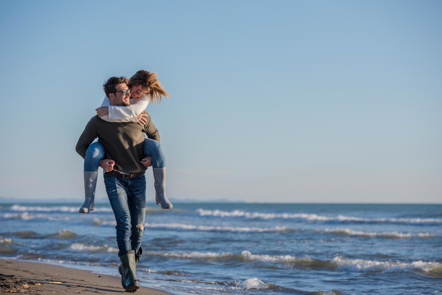 pareja divirtiéndose en la playa durante el otoño foto