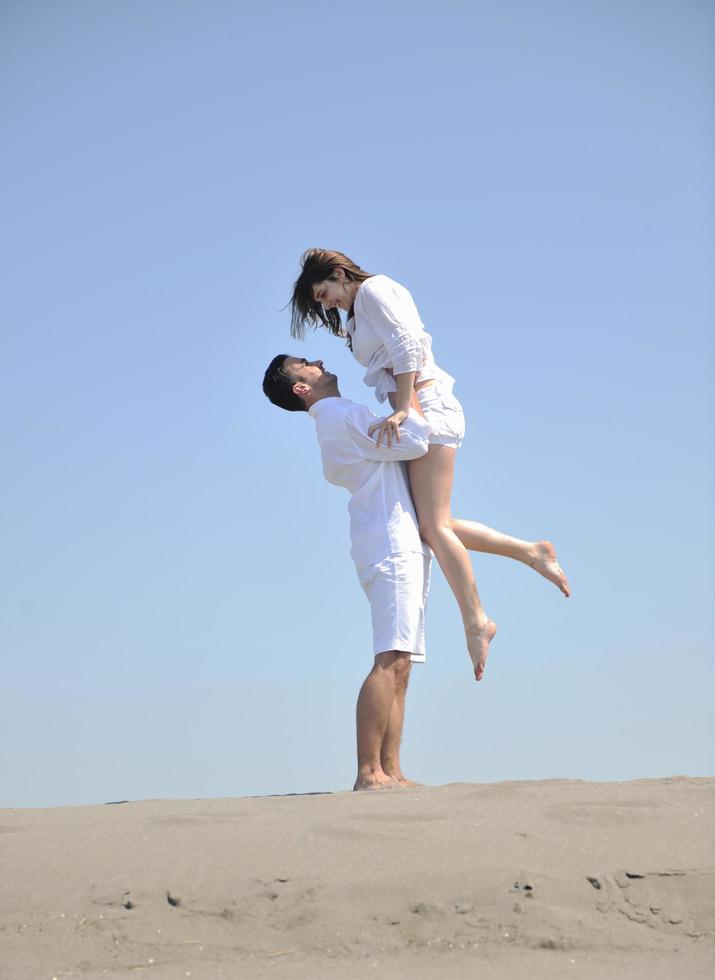 feliz pareja joven divertirse en la playa foto