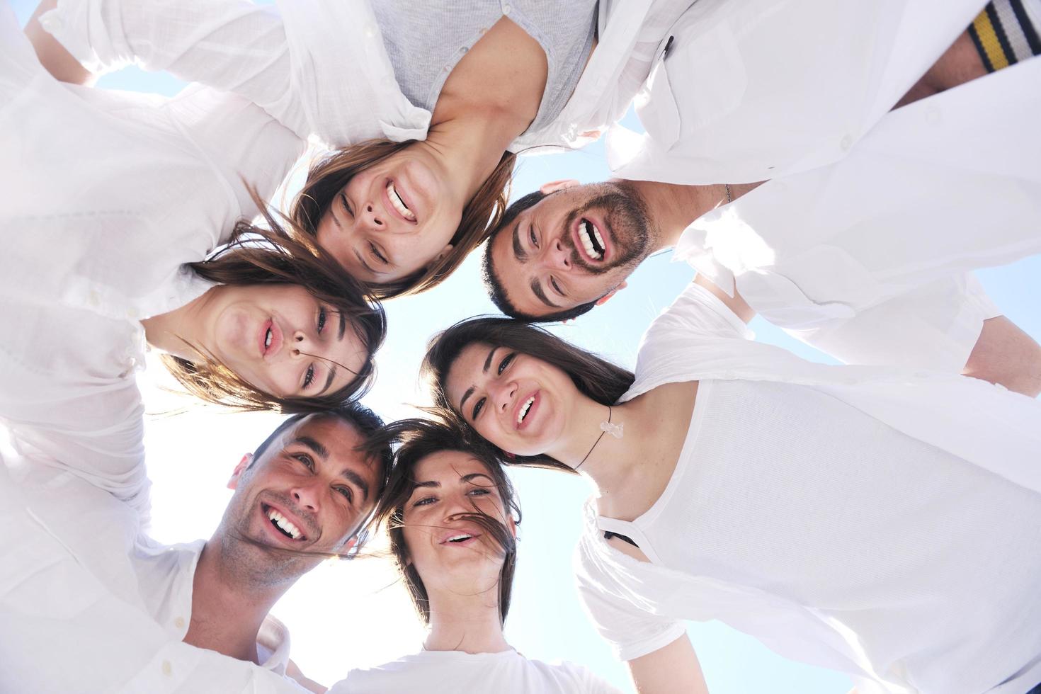 Group of happy young people in circle at beach photo